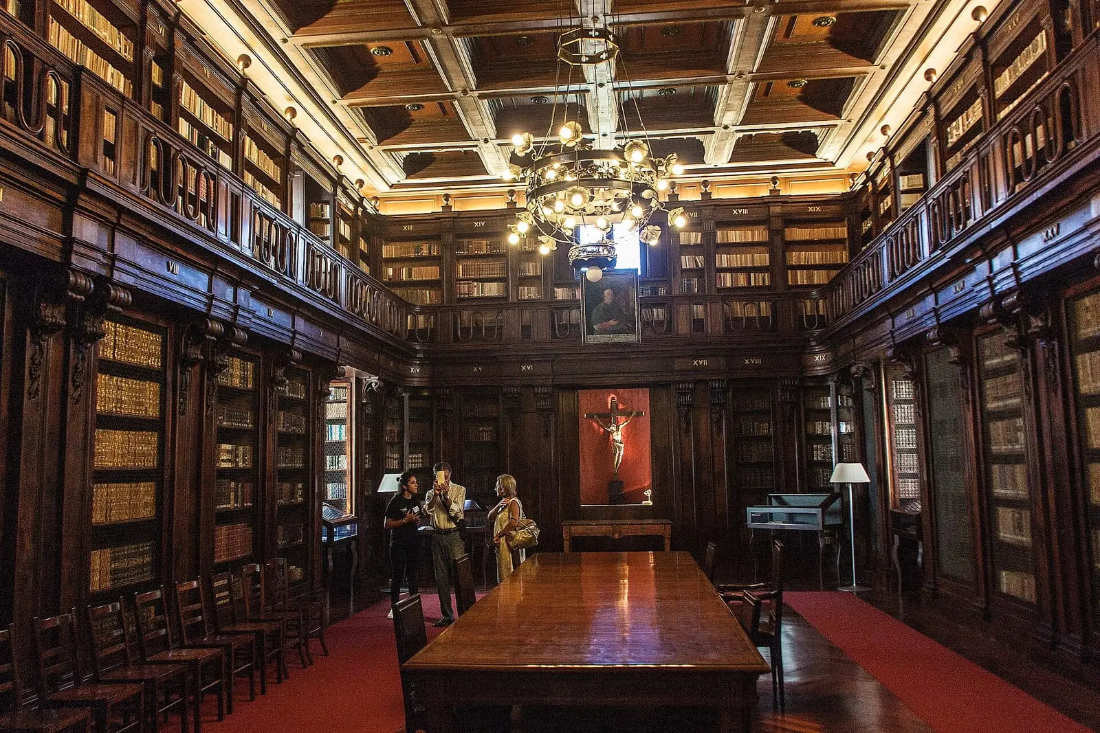 La biblioteca storica dell’Arcivescovado, con scaffali in legno e lampadario