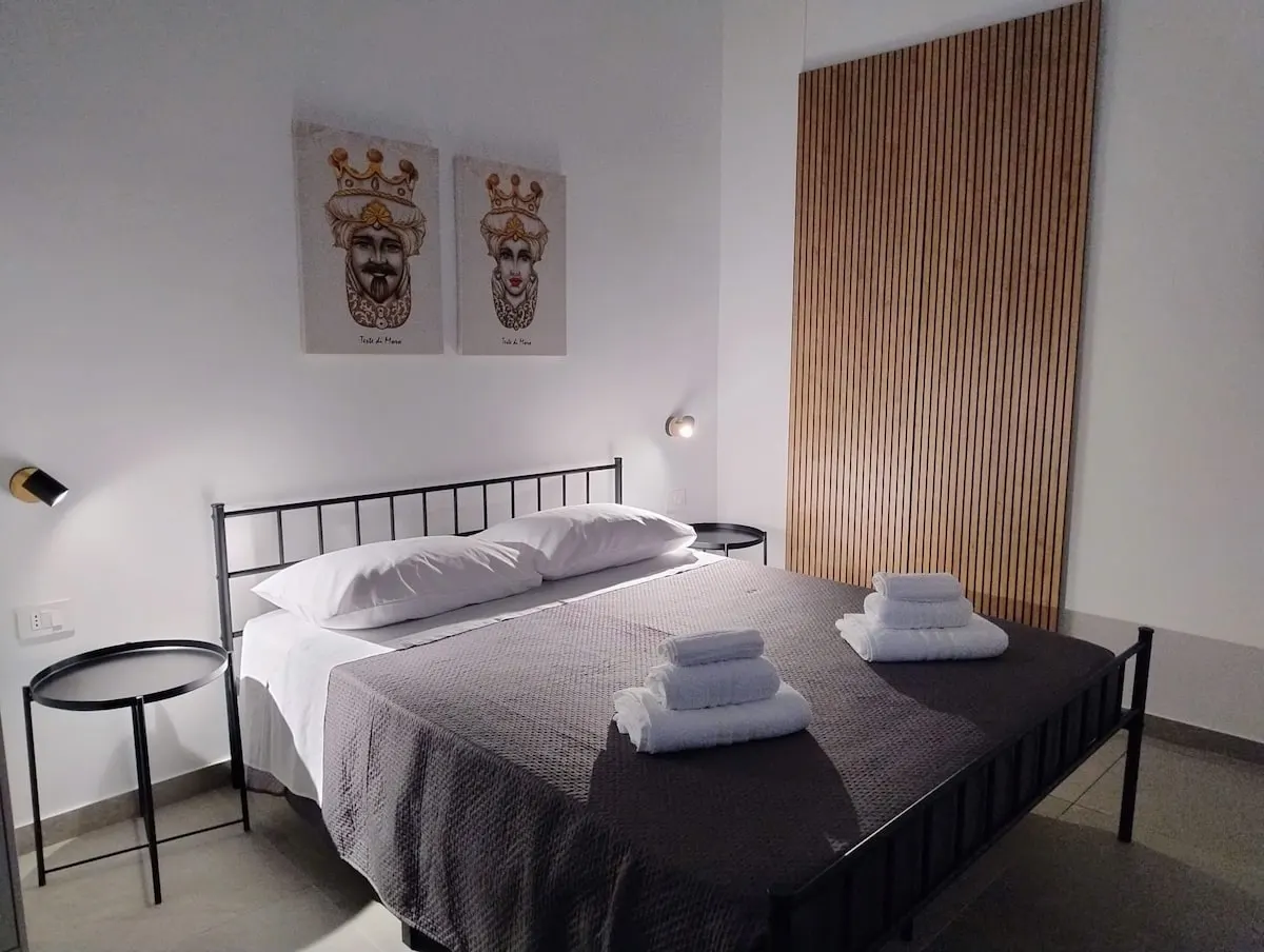 Camera con letto matrimoniale, quadri e parete in listelli di legno