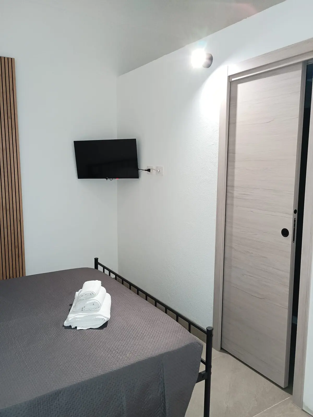 Angolo della camera con letto, televisione a parete e porta