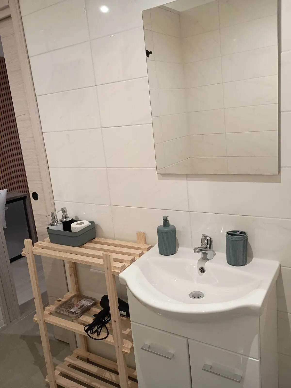 Bagno privato con lavabo, specchio e porta di legno