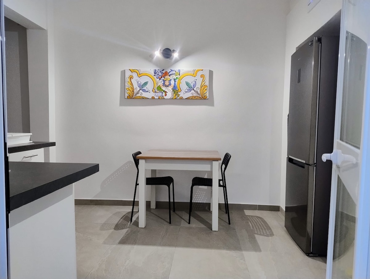 Zona pranzo con tavolo, due sedie, specchio e frigorifero