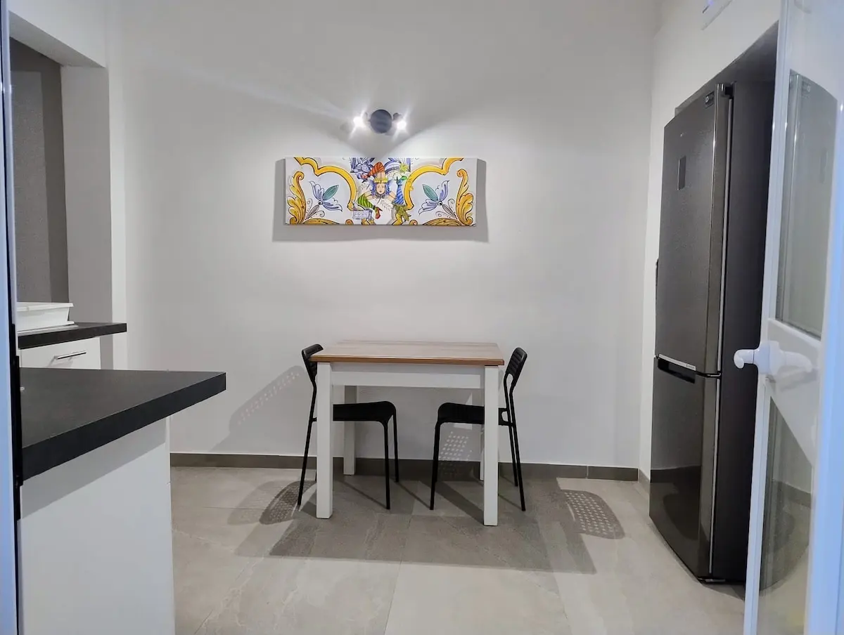 Zona pranzo con tavolo, due sedie, specchio e frigorifero