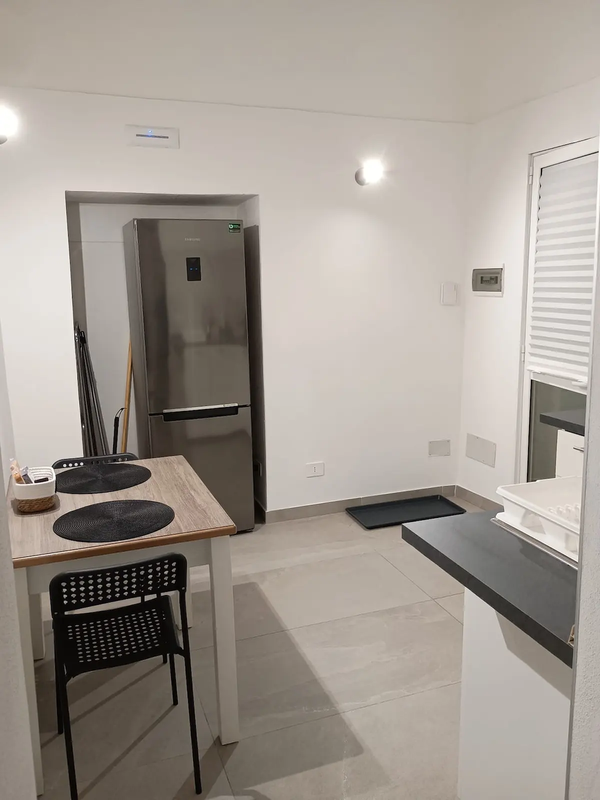 Cucinotto con piano a induzione, tavolo e porta d’ingresso