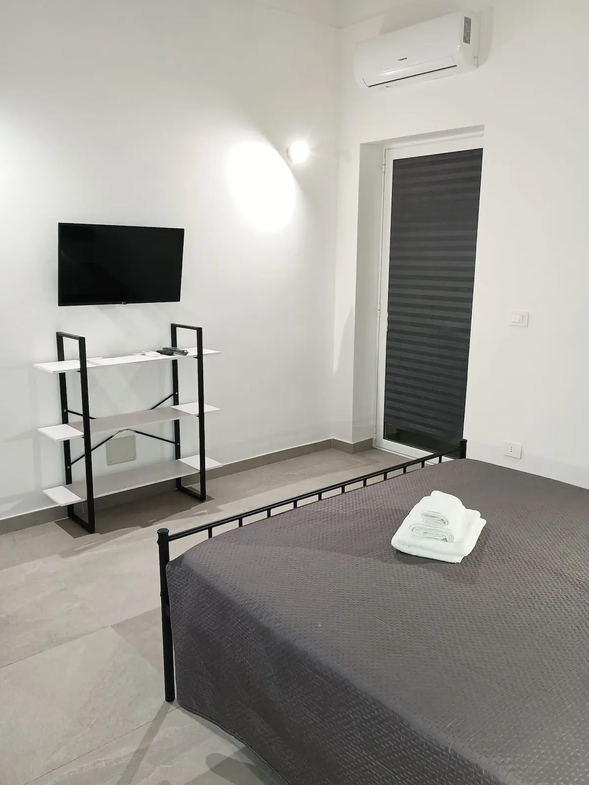 Letto matrimoniale con asciugamani piegati, televisione e climatizzatore