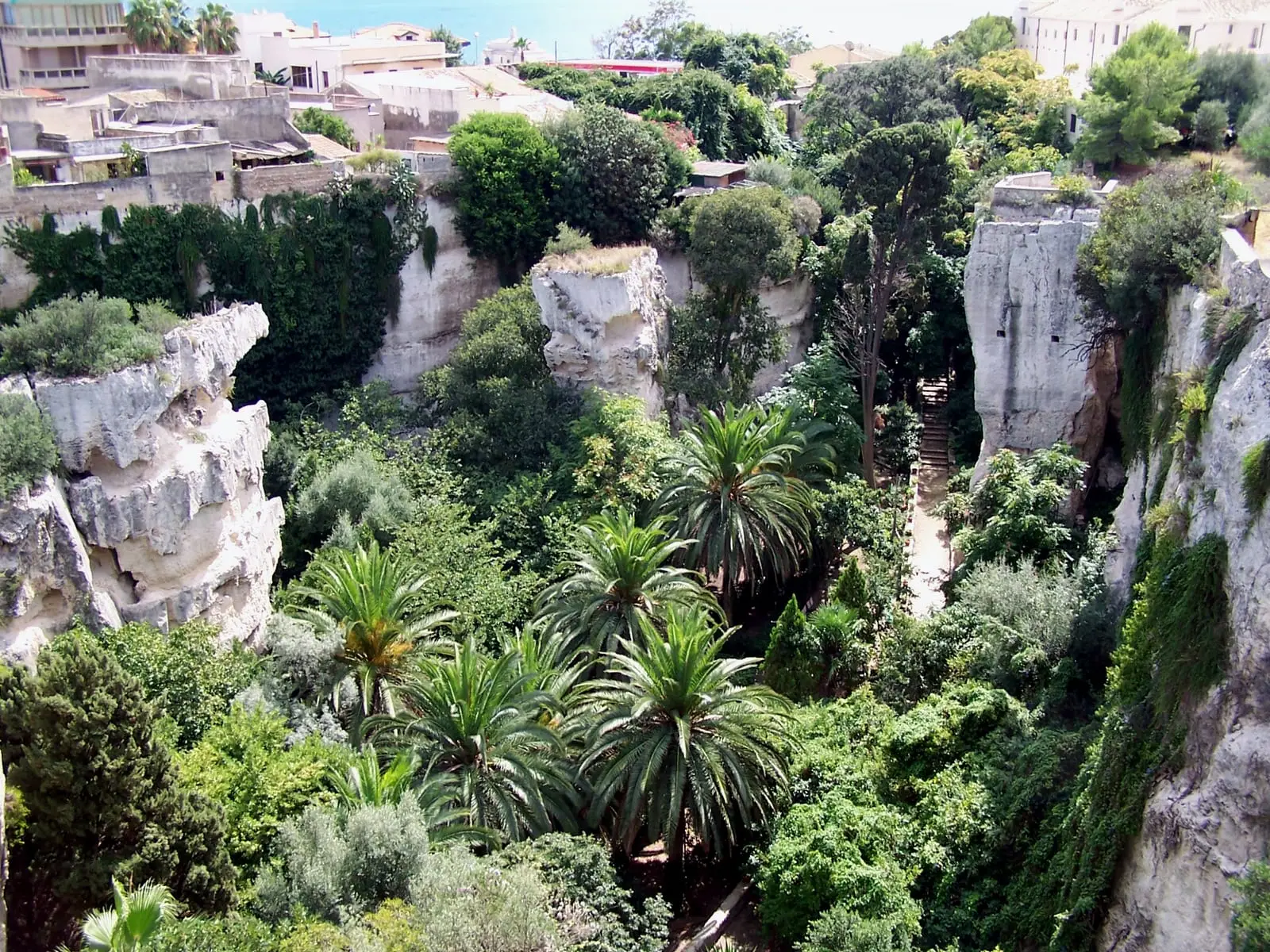 La Latomia dei Cappuccini, con il giardino, le palme e la parete di tufo
