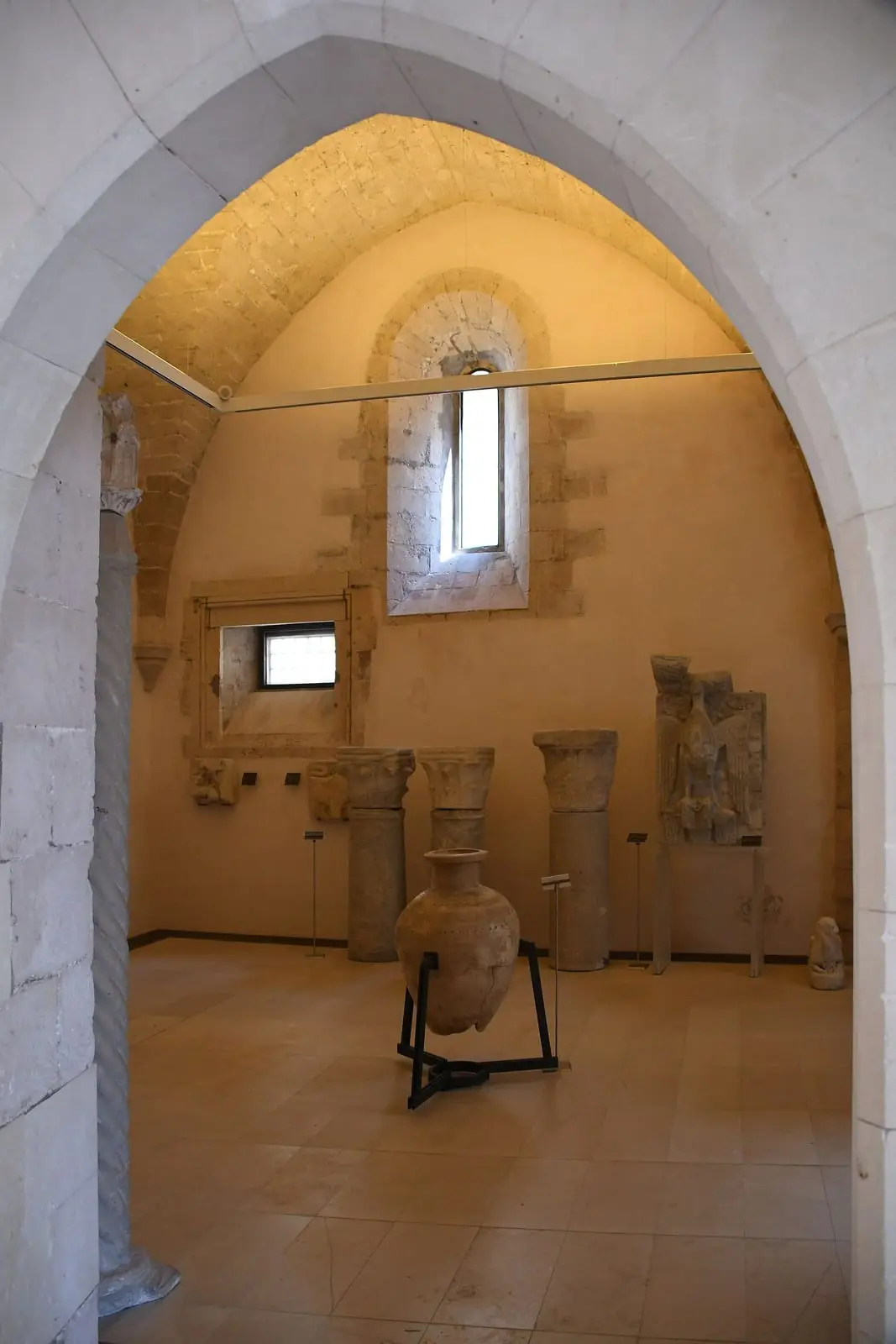 Una sala a volta di Palazzo Bellomo con le colonne in pietra e un’anfora
